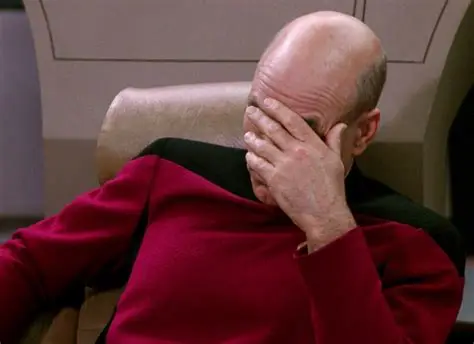 Captain Picard leaning on his elbow with the palm of his hand covering his face in dismay.